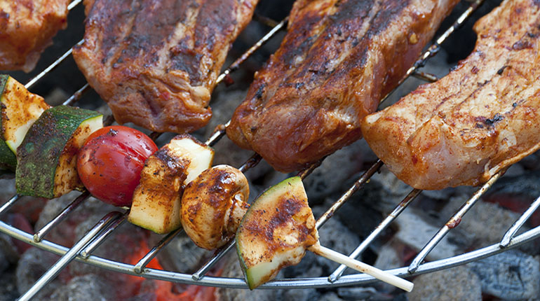 Broche te carne junto a cortes de res encima de una parrilla